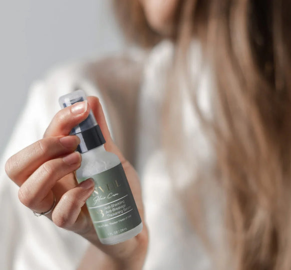 Woman holding unveil hair restorative growth serum.