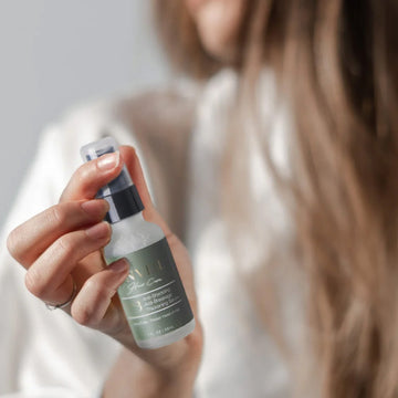 Woman holding unveil hair restorative growth serum.